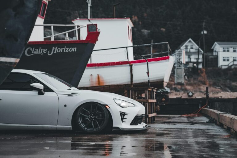 White sports car parked by docked boats, showcasing a blend of modern and nautical elements.